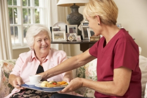 caregiver serving a meal to an elderly woman